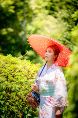 Portrait of a young woman wearing yukata summer kimono and holding Japanese traditional oil paper...