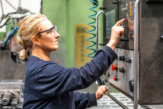Female factory worker operator working in numerical control sector, touching control panel, industrial factory