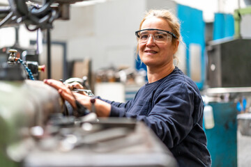 Portrait of female factory worker operator working in the control sector on a metal milling machine, industrial factory