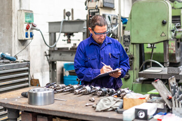 Factory worker operator in the numerical control sector making a report, industrial factory