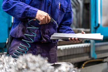 Factory worker operator in the numerical control sector cleaning a part with compressed air, metal...