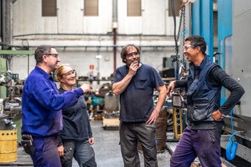 Team of workers laughing at the job of a metal industrial factory in the numerical control sector...