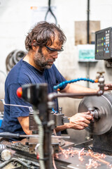 Worker in the metal industrial factory trade in the numerical control sector in CNC lathe processing
