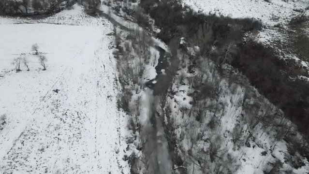 Footage of a snow covered countryside in mountion from above