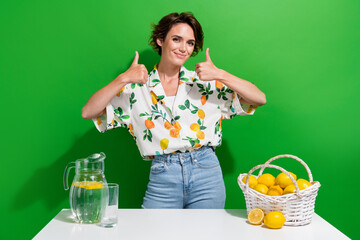 Photo of young funny girl double thumbs up confirm healthy nutrition benefits make citrus lemonade jug isolated on green color background
