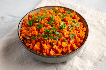 Homemade Smoky Spiced Carrot Rice with Parsley in a Bowl, side view.