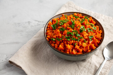 Homemade Smoky Spiced Carrot Rice with Parsley in a Bowl, side view. Copy space.