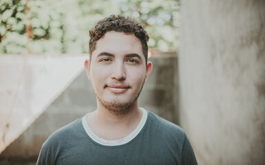 Obraz premium Portrait of cheerful young latin guy smiling at camera outdoors. Portrait of Latin American man looking and smiling at the camera