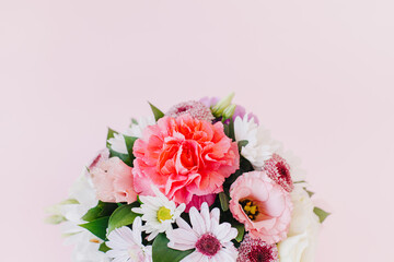 Beautiful bouquet of pink. violet and white flowers on a pink pastel background.