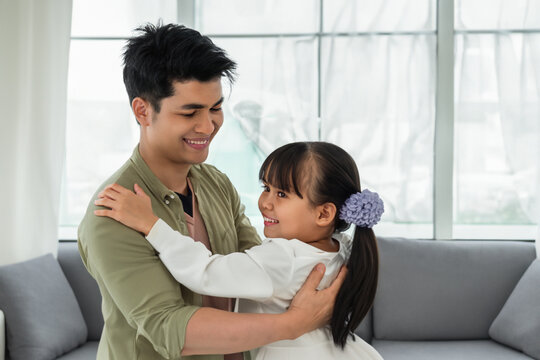 dad dances with his daughter. young happy dad dancing with his daughter, little girl with ponytails in a dress dancing with her dad