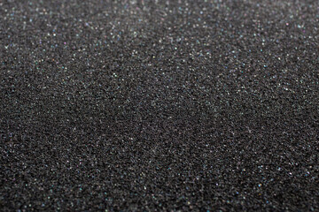 Black foam rubber. Closeup full-frame macro background with selective focus and shallow depth of...