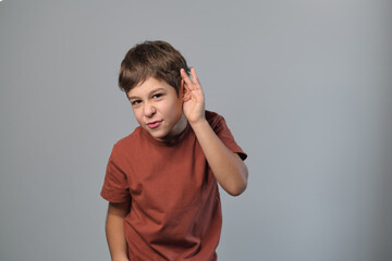 boy attentively listens, hand to ear, a gesture of focus. This image reflects the importance of listening in learning environments amid digital distractions.