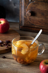 Homemade compote with apples and raisins in a glass cup on a wooden table