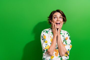 Photo of astonished cheerful girl wearing stylish clothes looking empty space offer proposition isolated on green color background