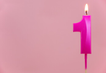 Pink birthday candle, number 1 burning on pink background. Copy space for text.