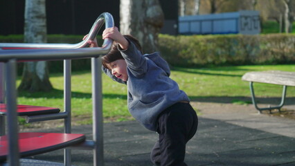 Child playing at playground carousel during autumn season. Little boy spinning in circles while holding on metal bar getting exercise and outdoor activity