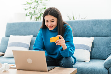 Focused woman using credit card while paying online on laptop
