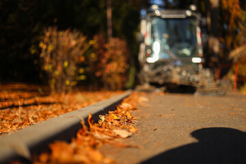 Cleaning the alleys in a park of a lot of fallen autumn leaves on the asphalt. Close up photo with...