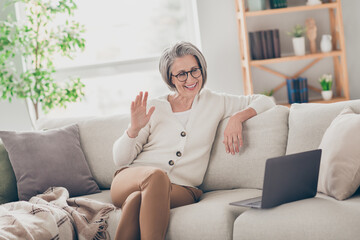 Photo of good mood friendly senior lady dressed white cardigan eyewear waving palm hi communicating...