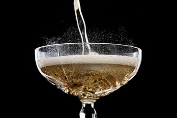 pouring champagne into a glass with bubbles, foam  on black background, for celebration