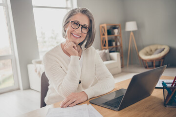 Photo of dreamy good mood elderly lady specialist wear white cardigan communicating modern device indoors apartment room