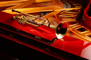Golden metallic brass trumpet music instrument on a open red pianoforte. Shallow depth of field