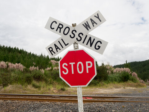 A red stop sign and railway crossing sign in wild landscape with rail track visible.New Zealand