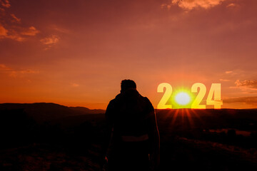 New year 2024 and new victories in business. Background showing man silhouette on mountain top and the beginning of New Year 2024.