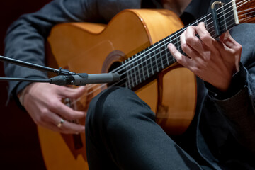 The singer plays an acoustic guitar. Close up of man's hands playing acoustic guitar