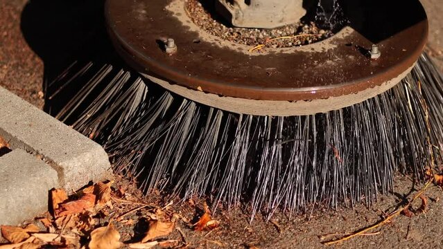 Cleaning the alleys in a park of a lot of fallen autumn leaves on the asphalt. Close up 4k video selective focus with a street utility car machine used to clean the public parks.
