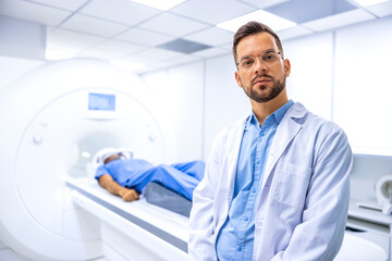 Naklejka na ściany i meble Portrait of serious doctor radiologist standing inside hospital MRI diagnostic center. Patient preparing for full body examination.
