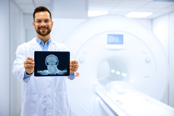 Portrait of expert radiologist holding X-ray image of brain inside MRI diagnostic center.