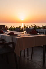 Outdoor restaurant with beautiful colorful sunset sky, sea view at the beach. Resort restaurant. Vertical orientation.