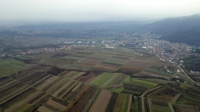Aerial view of agricultural fields near town Leskovac in Serbia in cold foggy day while snow falls