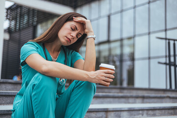 Tired depressed female scrub nurse wears face mask blue uniform gloves sits on hospital stairs outdoors. Exhausted sad black doctor feels burnout stress