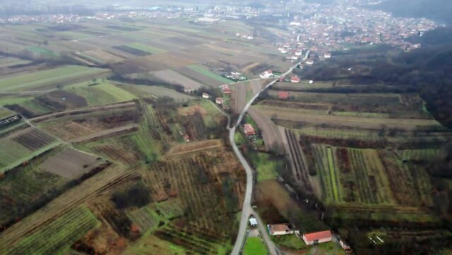 Aerial view of agricultural fields in town Leskovac at foothill of a mountain in Serbia in cold foggy day