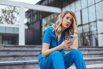 stressed modern medical practitioner woman in scrubs with stethoscope and cup of coffee outside near clinic. Female nurse suffering from a serious headache while working inside a hospital
