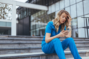 Shot of a young doctor looking distressed. Stressed modern medical practitioner woman in scrubs with stethoscope, medical mask and cup of coffee outside near clinic.