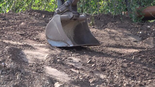Excavator bucket in operation. Excavation works. Power shovel moving earth and rocks. Digging building foundations