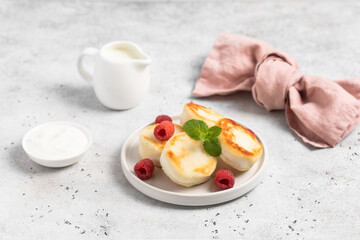 Cottage cheese fritters or syrniki served with raspberries.