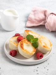 Cottage cheese fritters or syrniki served with raspberries.