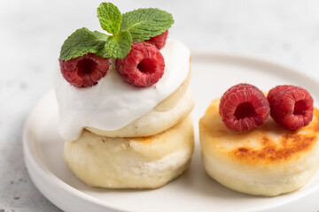 Cottage cheese fritters or syrniki served with raspberries.