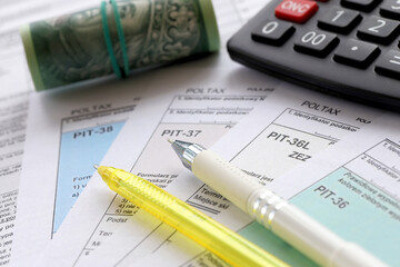 Declaration of the amount of earned income or incurred loss, PIT-36, PIT-36L, PIT-37 and PIT-38 tax forms on accountant table with pen and polish zloty money bills close up