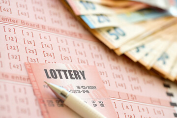 Lottery ticket and gambling receipt on table with pen and European Union euro money bills close up