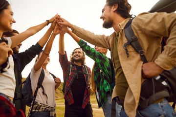 Team of happy friends go on hike and give each other high five. Group of active cheerful positive...
