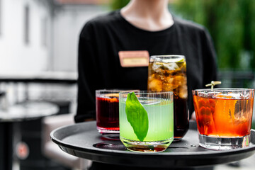 waiter with a tray of cocktails in a summer cafe
