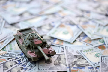 Obraz na płótnie Canvas Toy tank on US hundred dollar bills banknotes close up. The concept of war costs, military spending and economic crisis
