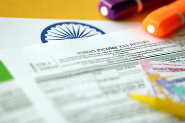Indian income tax return blank form with pen and indian rupees bills on indian country flag close...