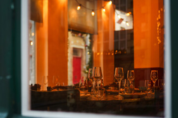 A restaurant table set for Christmas dinner is visible through the window. Xmas atmosphere.