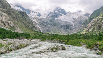The bubbling clear water of a mountain river with large stones high in the mountains. Clean water flows down from a glacier in the mountains. Landscape in the mountains. Uncontaminated environment.